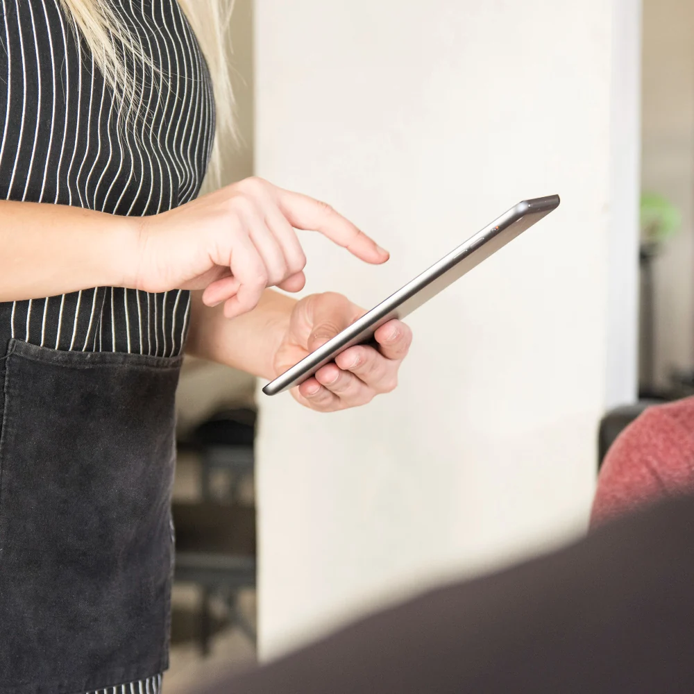 A store associate in a striped apron working on a tablet